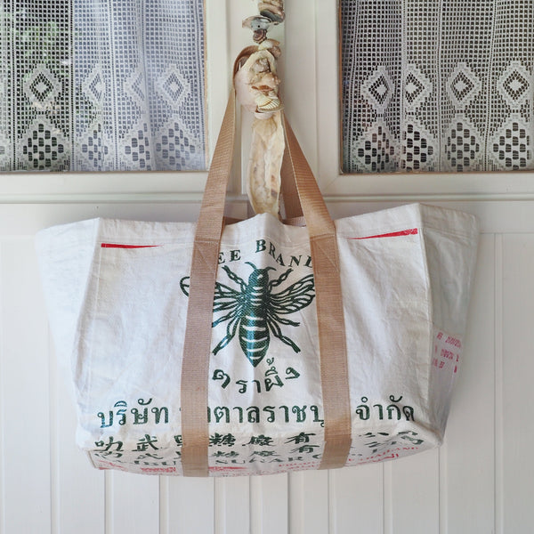 weiße Badetasche mit Bienenmotiv hängt an einer Tür