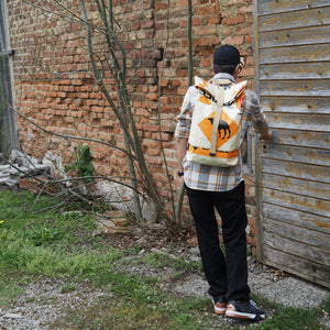 Mann mit beige-orangem Rucksack am Rücken schließt Türe auf