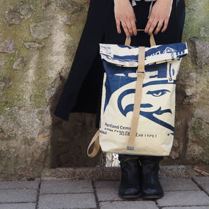 Frau hält beigen Rucksack mit Adlermotiv in der Hand