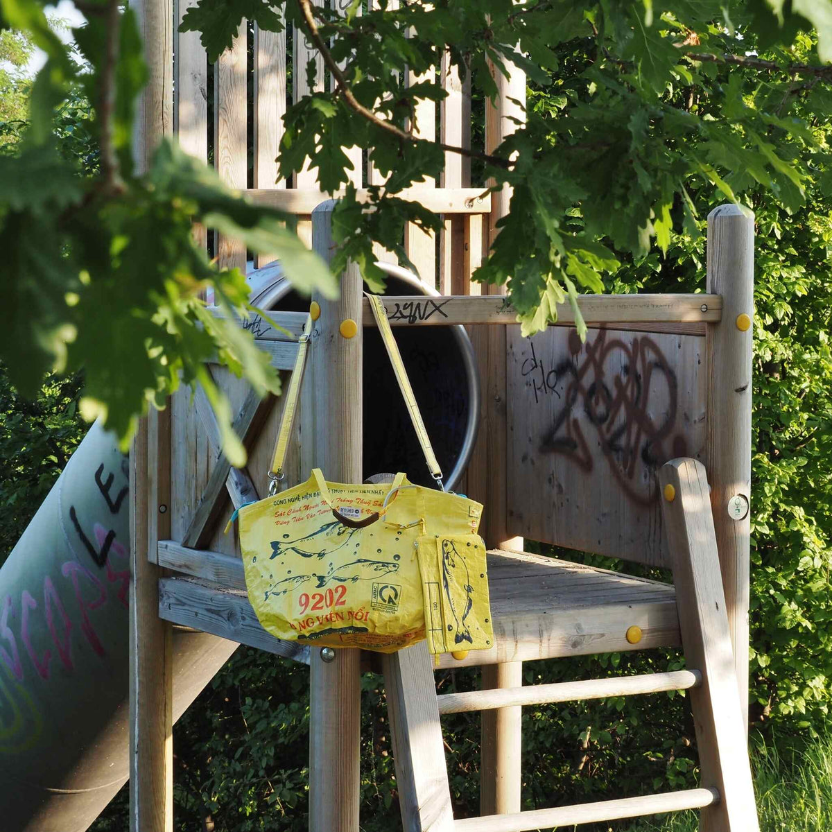nachhaltige Badetasche - neu mit Zipp und Gurt in gelb hängt am Spielplatz im Set mit Bag-in-Bag
