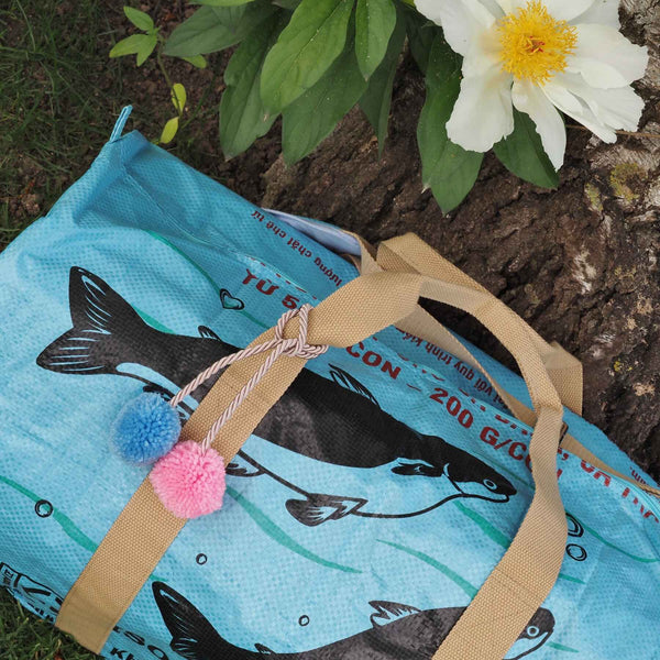 blau-rosa Bommeln an hellblauer Sporttasche