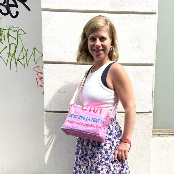 Frau mit blau-rosa Rock trägt die Umhängetasche in rosa-blau