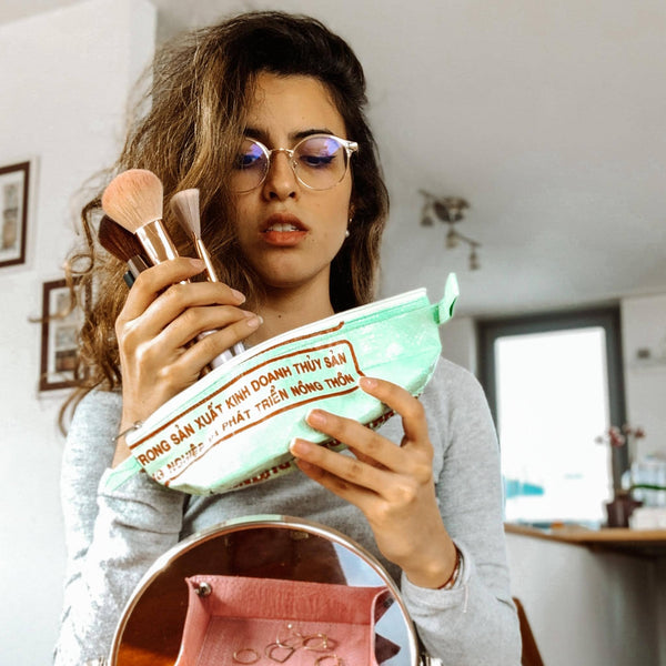 Frau gibt Cosmetic Utensilien in das hellgrüne Pencil Case