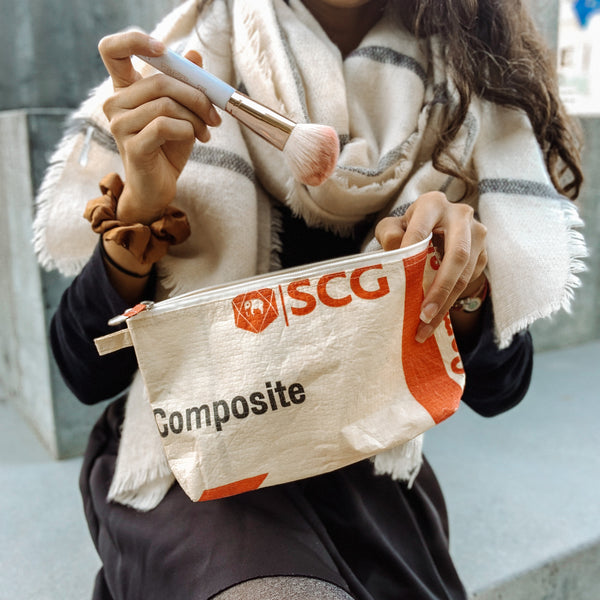 Frau gibt MakeUp Pinsel in ein beiges Kosmetiktäschchen