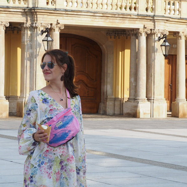 Eine Frau mit buntem Kleid trägt die Bum Bag quer über die Schulter und hält ein Eis in der Hand
