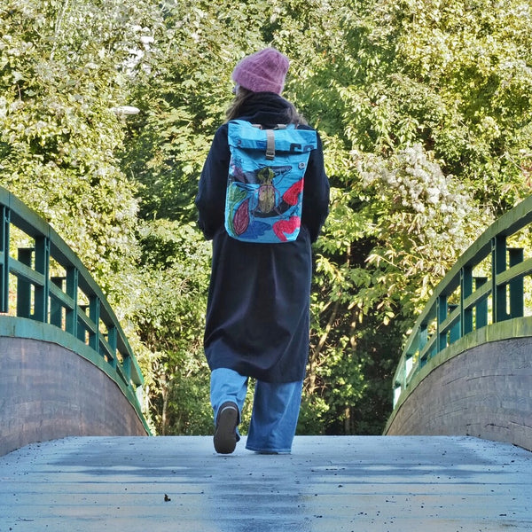 Frau geht mit blauen ART EDITION Rucksack am Rücken über eine Brücke