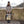 Load image into Gallery viewer, Frau mit beige-blauem Rucksack in der Hand steht in der Sonne und lächelt
