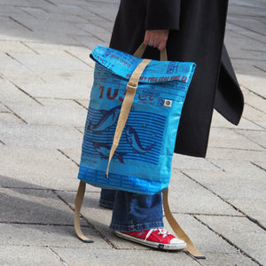 blauer Rucksack wird in der Hand gehalten