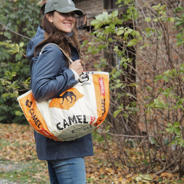 Frau mit Kappe und langen Haaren trägt Soulmate Shopper in beige-orange mit Kamel Motiv über die Schulter