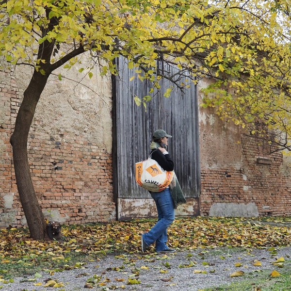 Frau mit Kappe trägt Soulmate Shopper in beige-orange mit Kamel Motiv über die Schulter