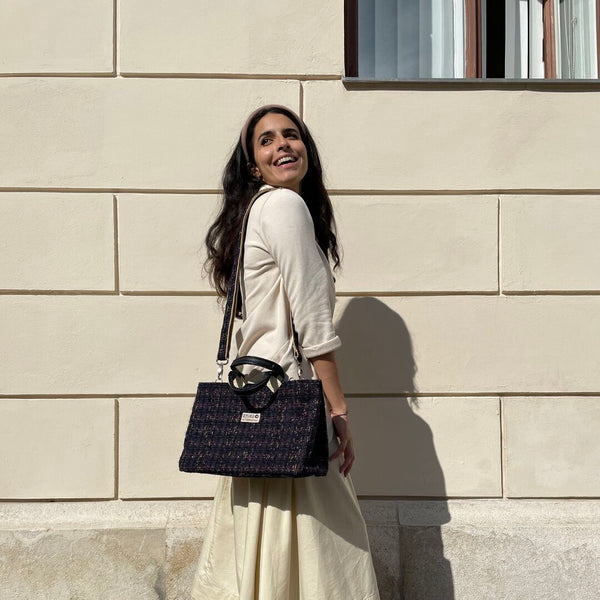 strahlend lachende Frau mit langen dunklen Haaren und hellem Outfit trägt die Isolde Bag in dunkelblau um die Schulter gehängt