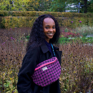 junge Frau lacht und trägt lila-schwarze Bauchtasche quer um den Körper