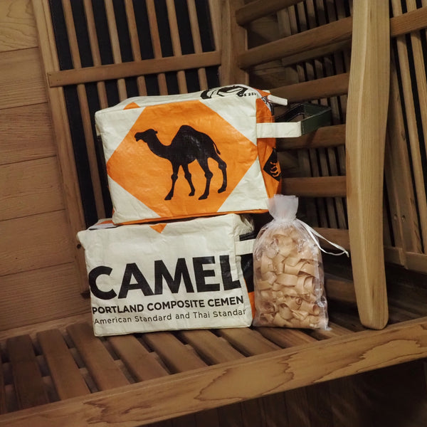 zwei Waschbeutel in beige-orange (einmal mit Tiermotiv, einmal mit Schriftzug) stehen in einer Sauna