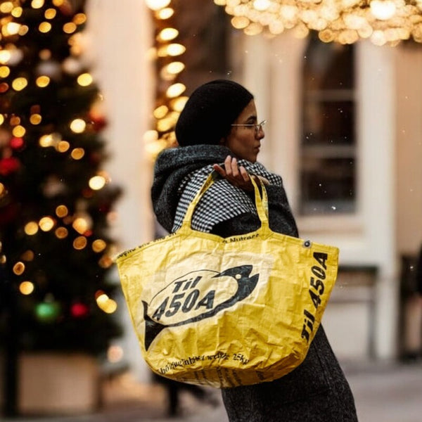 Frau mit Haube trägt gelbe Soulmate, weihnachtliches Ambiente / background AI generated