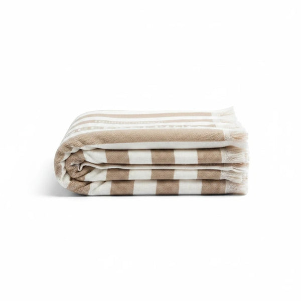 REFISHED gestreiftes Strandtuch aus recyceltem Material in Beige und Weiß mit Fransen, gefaltet auf weißem Grund.