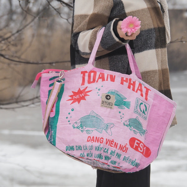 Frau trägt rosa Soulmate um den Arm und hält eine rosa Blume in der Hand