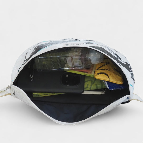 nachhaltig gefertigte Bauchtasche - Bum Bag XL - in weiß mit schwarzen Fischen - befüllt mit Buch, Handy, Trinkflasche, Taschentüchern