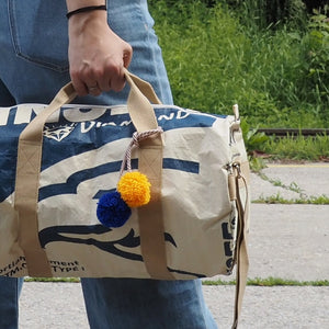 Frau hält nachhaltige Sporttasche mit Bommeln in der Hand