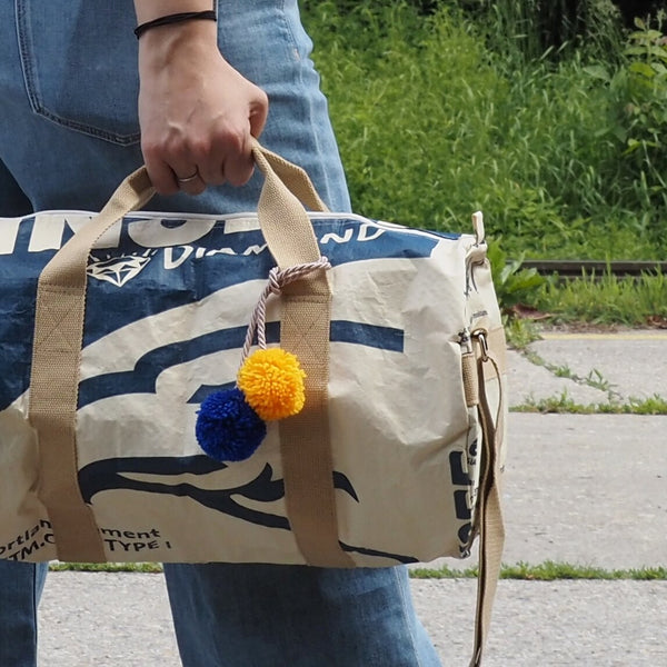 Frau hält nachhaltige Sporttasche mit Bommeln in der Hand